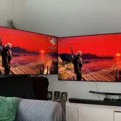 Dwa telewizory z grą Wiedźmin 3, z widokiem na zachód słońca i Geralta. Obraz na ekranach jest żywy dzięki technologii miniled.