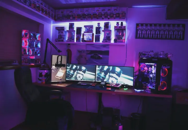 Zestaw komputerowy z podświetleniem RGB, idealny do gier z wykorzystaniem **DirectX**. Na półkach figurki Funko Pop i gadżety Star Wars.