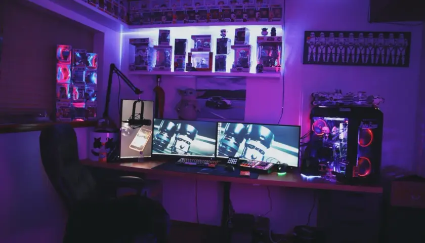 Zestaw komputerowy z podświetleniem RGB, idealny do gier z wykorzystaniem **DirectX**. Na półkach figurki Funko Pop i gadżety Star Wars.
