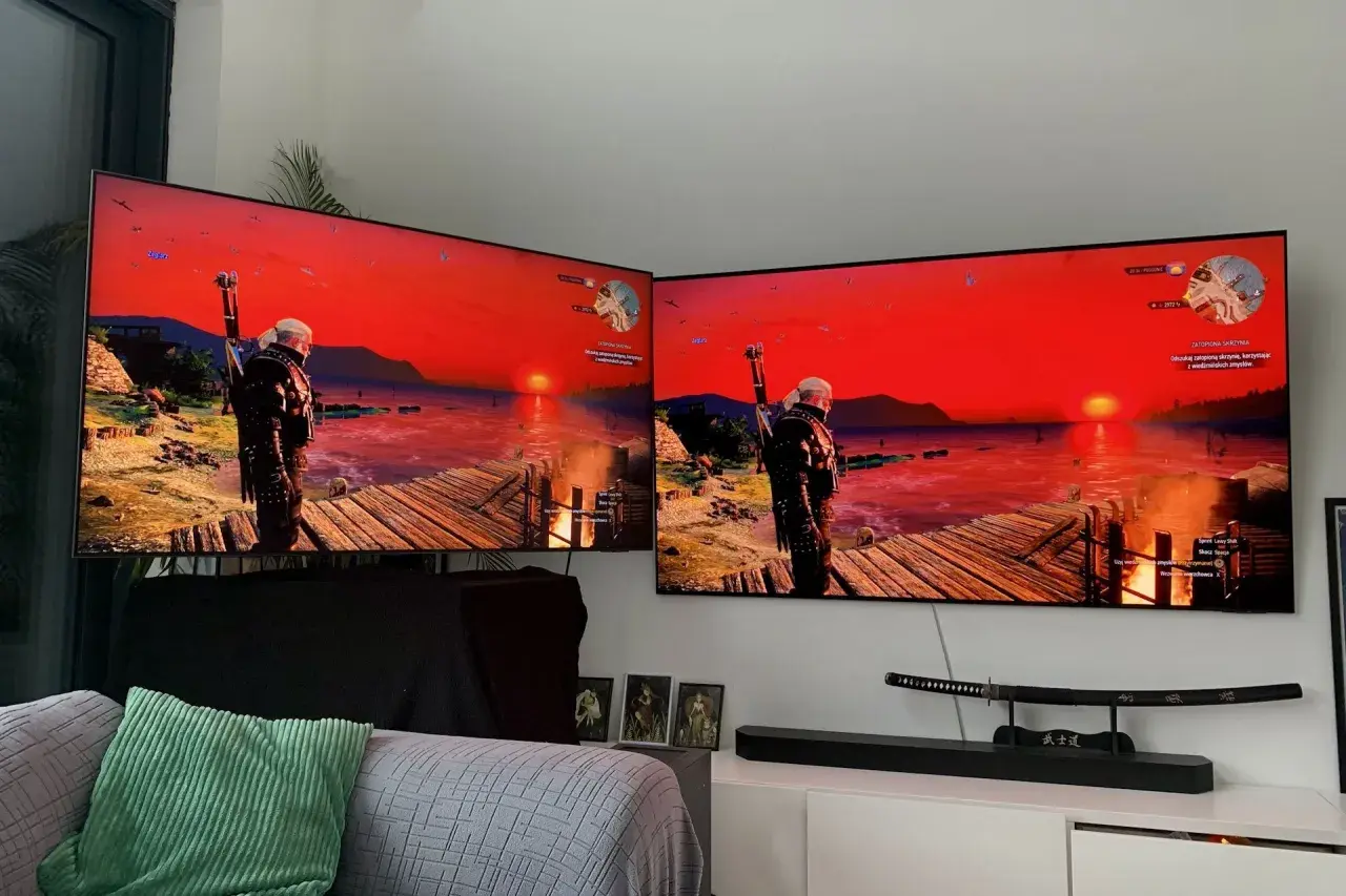Dwa telewizory z grą Wiedźmin 3, z widokiem na zachód słońca i Geralta. Obraz na ekranach jest żywy dzięki technologii miniled.